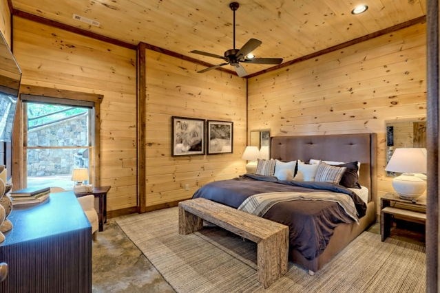 bedroom featuring ceiling fan, wooden walls, wood ceiling, and a high ceiling