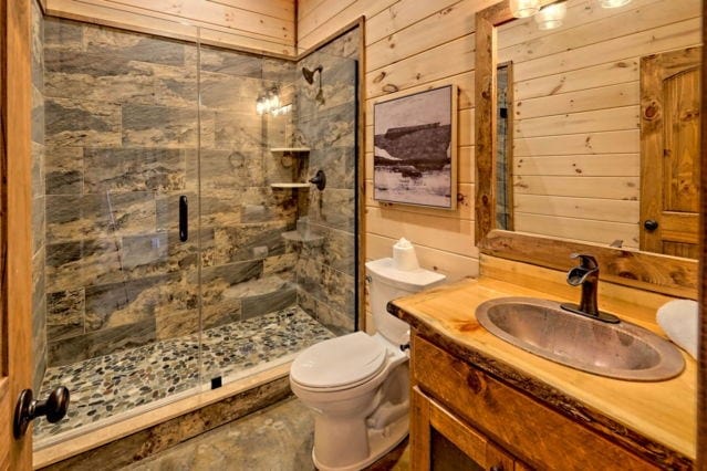 bathroom featuring wooden walls, toilet, a stall shower, and vanity