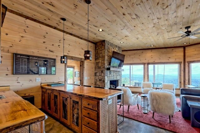 kitchen featuring ceiling fan, pendant lighting, wood ceiling, wooden walls, and a fireplace