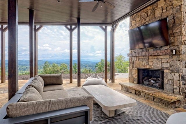 sunroom / solarium featuring ceiling fan, wood ceiling, and an outdoor stone fireplace