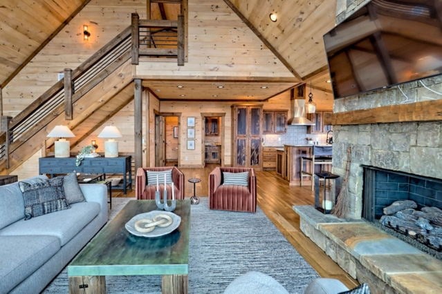 living room with wood ceiling, wood-type flooring, wooden walls, high vaulted ceiling, and a fireplace