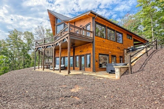 rear view of property featuring a patio area, a deck, and a hot tub