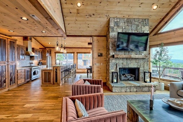 living room featuring wood walls, light hardwood / wood-style flooring, wooden ceiling, a fireplace, and vaulted ceiling