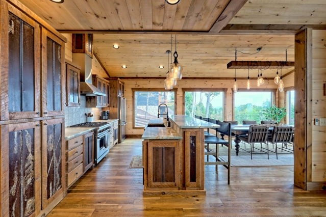 kitchen with hanging light fixtures, a center island with sink, extractor fan, appliances with stainless steel finishes, and dark hardwood / wood-style flooring