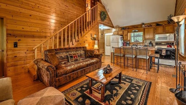 living room featuring wooden walls, high vaulted ceiling, and light wood-type flooring