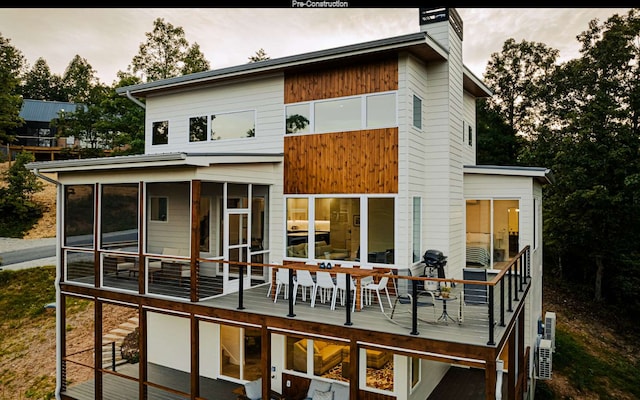 back of property with a wooden deck and a sunroom