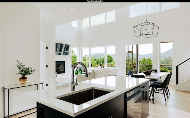 kitchen with a healthy amount of sunlight, a center island with sink, decorative light fixtures, and sink