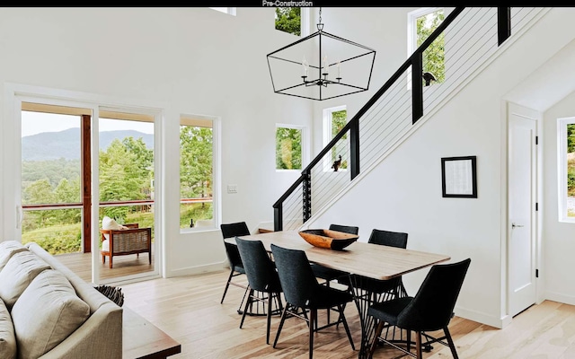 dining area featuring a healthy amount of sunlight, light hardwood / wood-style flooring, a notable chandelier, and a towering ceiling