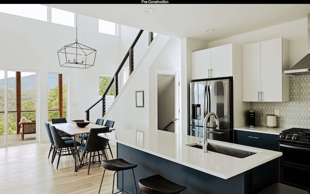 kitchen with hanging light fixtures, stainless steel refrigerator with ice dispenser, backsplash, sink, and light hardwood / wood-style floors