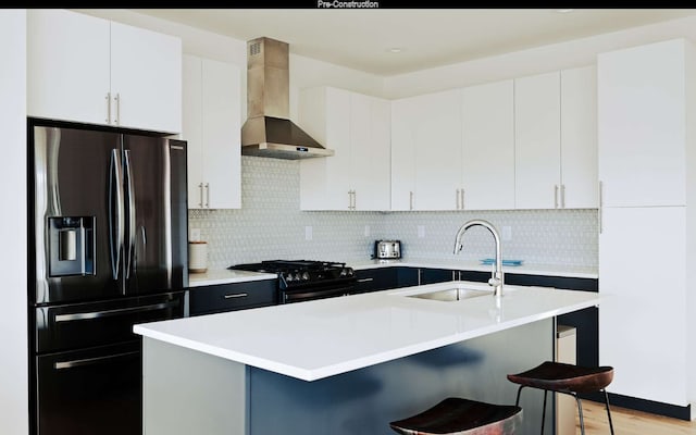 kitchen with a kitchen breakfast bar, black range with gas cooktop, wall chimney range hood, sink, and stainless steel fridge with ice dispenser