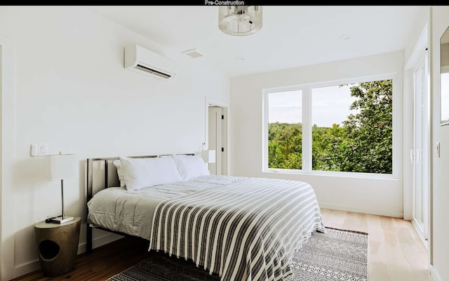 bedroom with a wall unit AC, hardwood / wood-style floors, and multiple windows