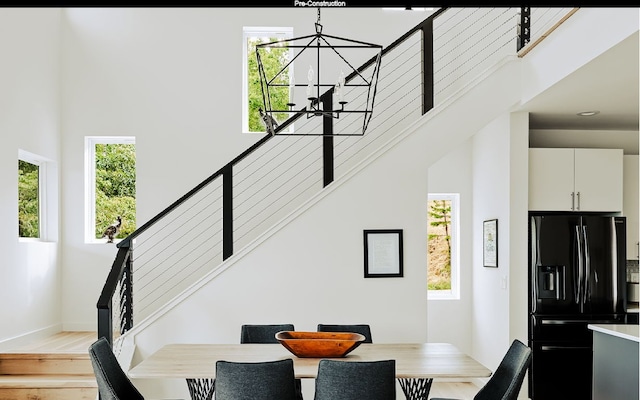 dining area with a chandelier, a high ceiling, and light wood-type flooring