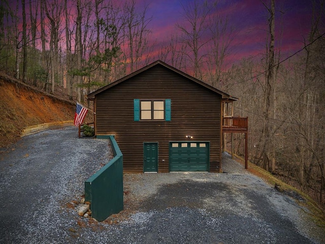 property exterior at dusk with a wooden deck and a garage