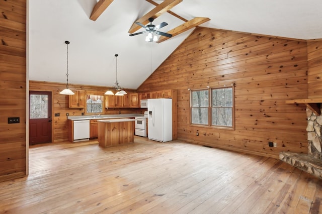 kitchen with a kitchen island, wood walls, decorative light fixtures, light hardwood / wood-style floors, and white appliances