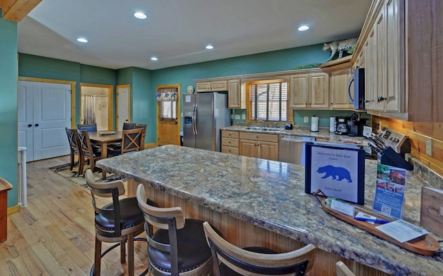 kitchen featuring a breakfast bar area, recessed lighting, light wood-style flooring, stainless steel appliances, and a sink