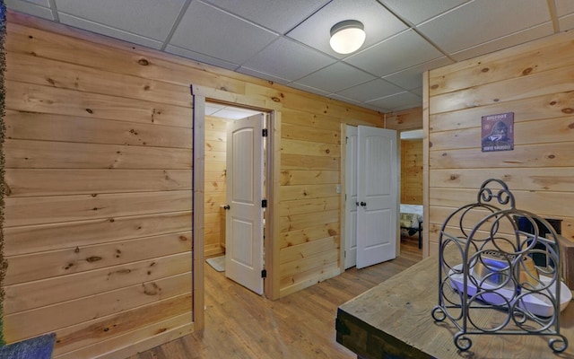 interior space featuring wooden walls, wood finished floors, and a drop ceiling