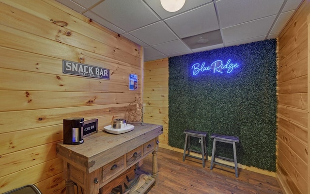 interior space with wood finished floors, wood walls, and a paneled ceiling