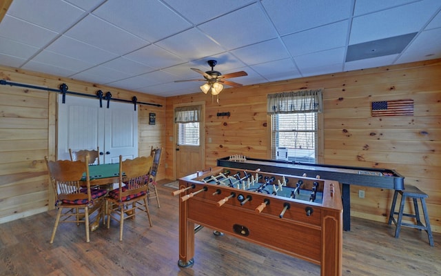 recreation room featuring wood walls, a barn door, and wood finished floors