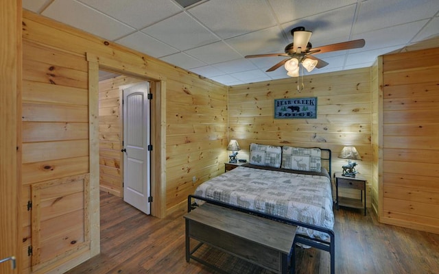 bedroom featuring wooden walls, dark wood-type flooring, and a paneled ceiling