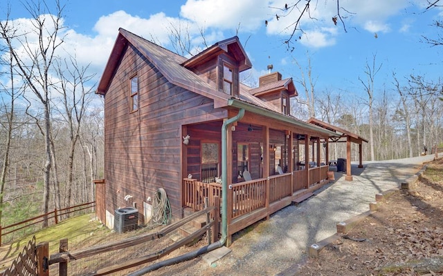 view of side of property featuring metal roof, central AC, and fence