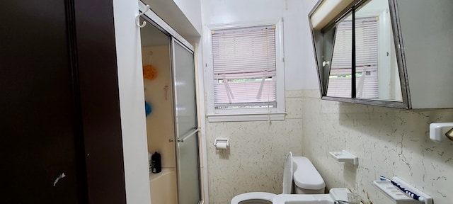 bathroom with toilet and a shower with door