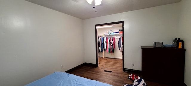 bedroom featuring a spacious closet, a closet, ceiling fan, and dark hardwood / wood-style floors