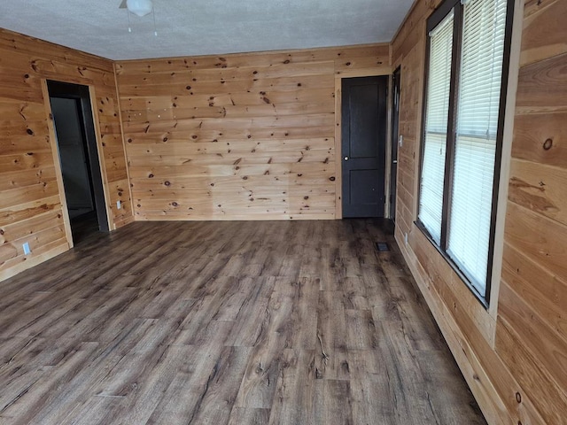 unfurnished room with hardwood / wood-style floors and wooden walls