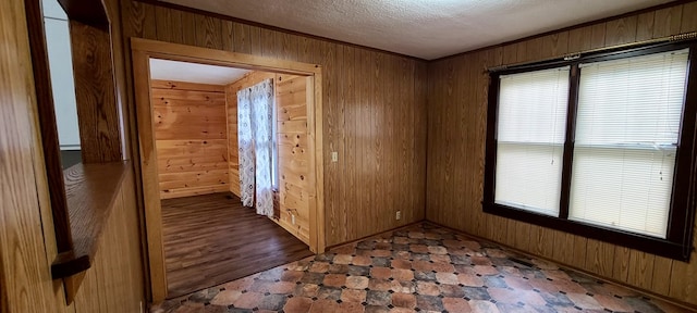 unfurnished room with a textured ceiling and wooden walls