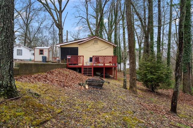 back of house featuring a deck and an outdoor fire pit