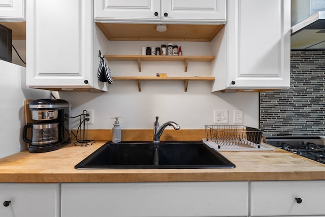 kitchen featuring wood counters, white cabinets, and a sink