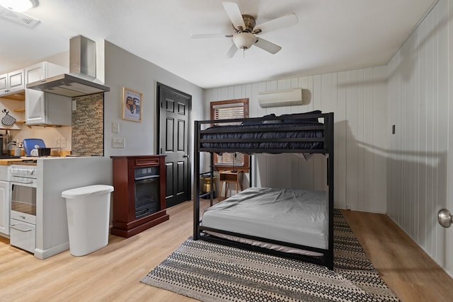 bedroom with light wood-style flooring, visible vents, a ceiling fan, and a wall mounted air conditioner