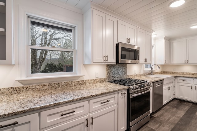 kitchen with stainless steel appliances, wood ceiling, white cabinetry, and a sink