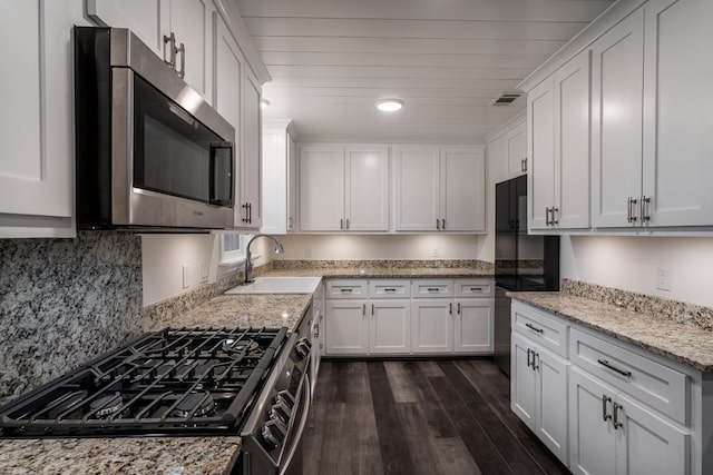 kitchen with dark wood-style flooring, a sink, white cabinets, stainless steel microwave, and gas range