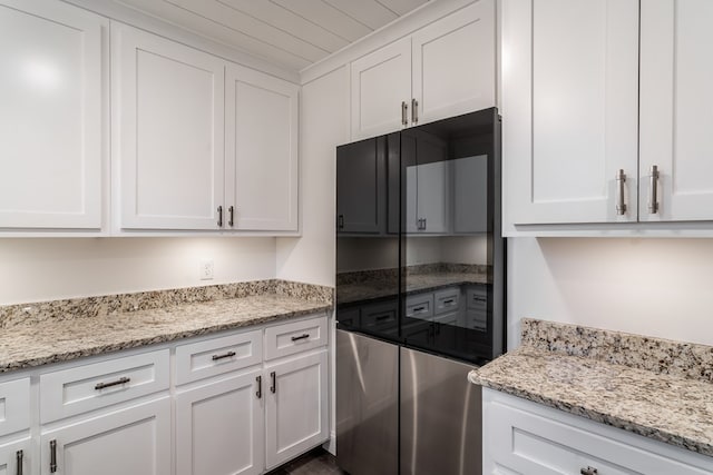 kitchen featuring light stone countertops and white cabinets