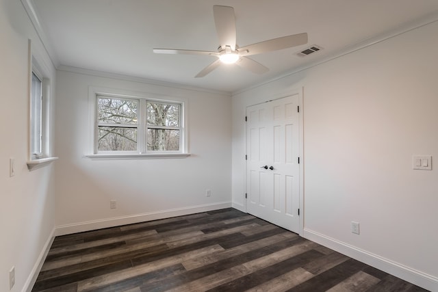 unfurnished bedroom with visible vents, baseboards, a closet, dark wood finished floors, and crown molding