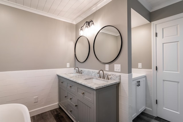 full bathroom featuring a wainscoted wall, ornamental molding, a sink, and wood finished floors