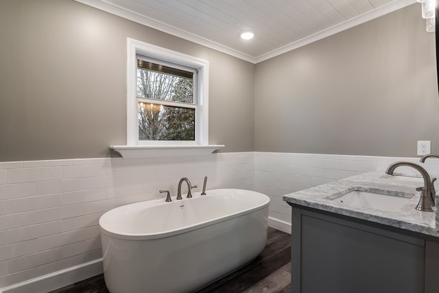 bathroom with a soaking tub, wood finished floors, crown molding, and wainscoting