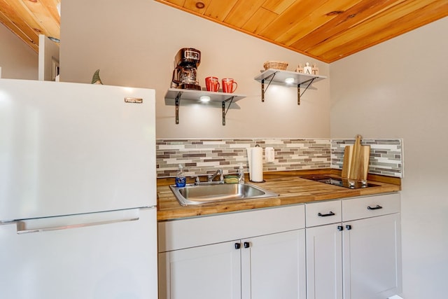 kitchen featuring decorative backsplash, sink, white refrigerator, wooden ceiling, and white cabinetry