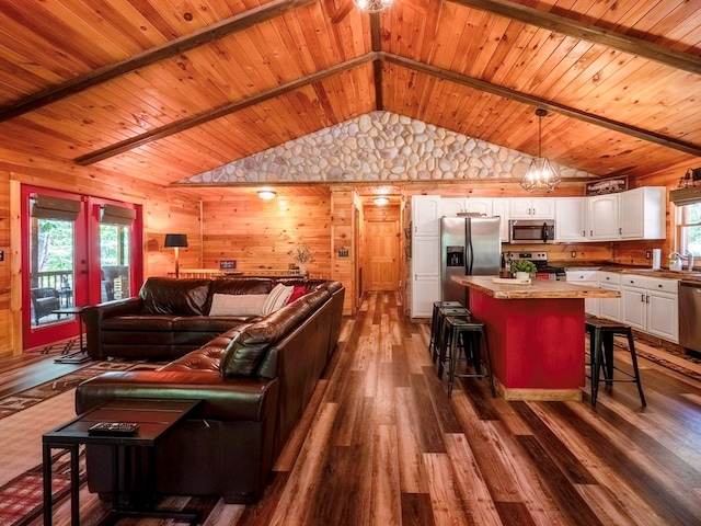 living room with dark wood-type flooring, wooden walls, vaulted ceiling with beams, a notable chandelier, and wood ceiling