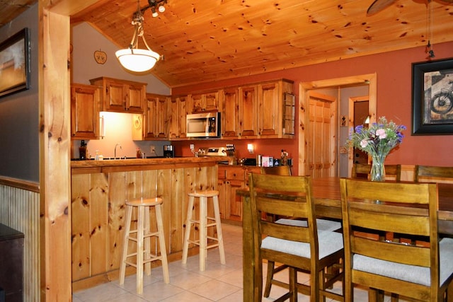 115 Black Oak Ridge Rd, Blue Ridge, GA 30513 - kitchen with stainless steel microwave, lofted ceiling, wood ceiling, light tile patterned flooring, and a breakfast bar
