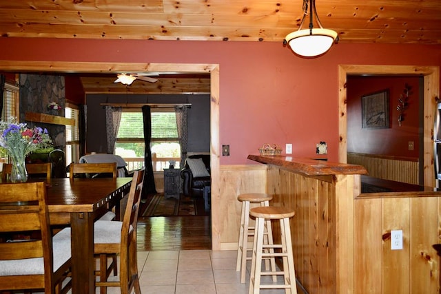 115 Black Oak Ridge Rd, Blue Ridge, GA 30513 - dining room with a wainscoted wall, a bar, wood ceiling, light tile patterned flooring, and a ceiling fan