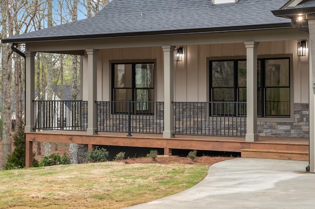 exterior space with a porch, a yard, stone siding, roof with shingles, and board and batten siding