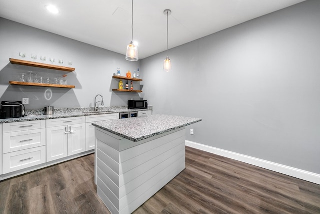 kitchen featuring dark wood-style flooring, open shelves, black microwave, a sink, and white cabinetry