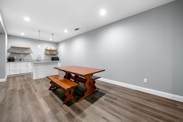 dining room featuring indoor wet bar, recessed lighting, baseboards, and wood finished floors