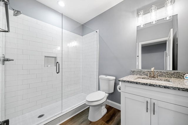 bathroom with vanity, wood finished floors, toilet, baseboards, and a shower stall