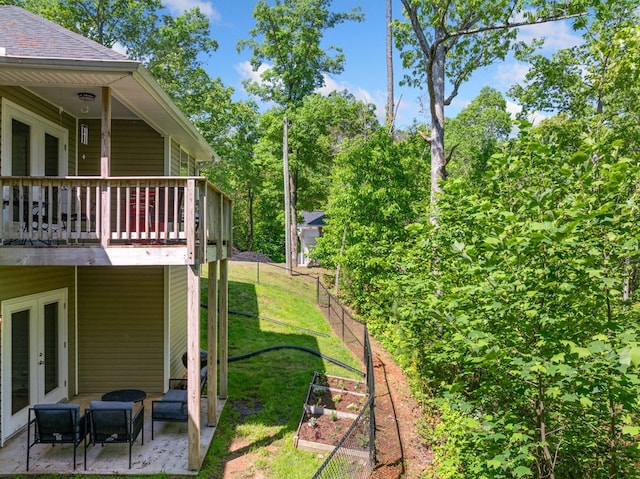 view of yard with a patio, fence, french doors, and a vegetable garden