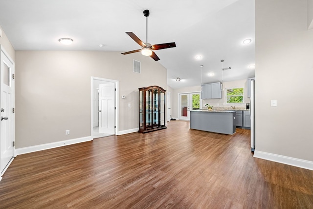 unfurnished living room featuring a ceiling fan, visible vents, high vaulted ceiling, baseboards, and dark wood-type flooring
