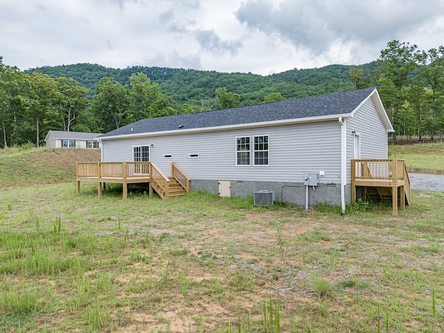 rear view of house featuring a deck, a yard, and central AC