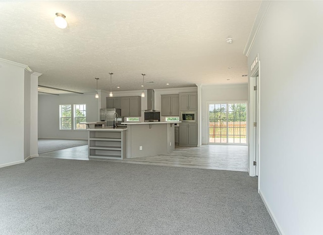 unfurnished living room with sink, a textured ceiling, and ornamental molding