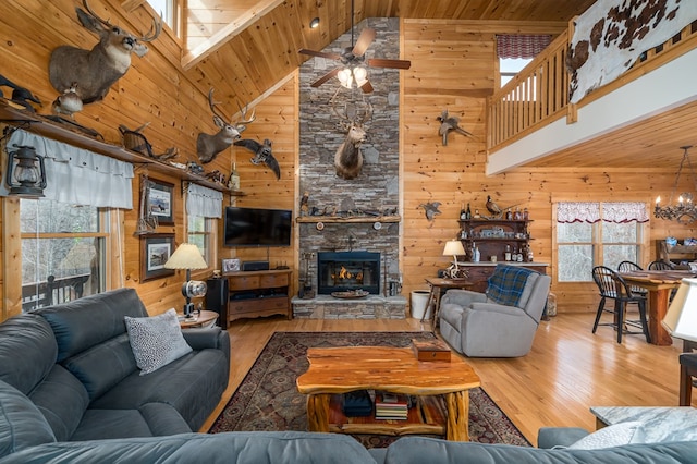 living room featuring a stone fireplace, wooden ceiling, wood finished floors, and wooden walls